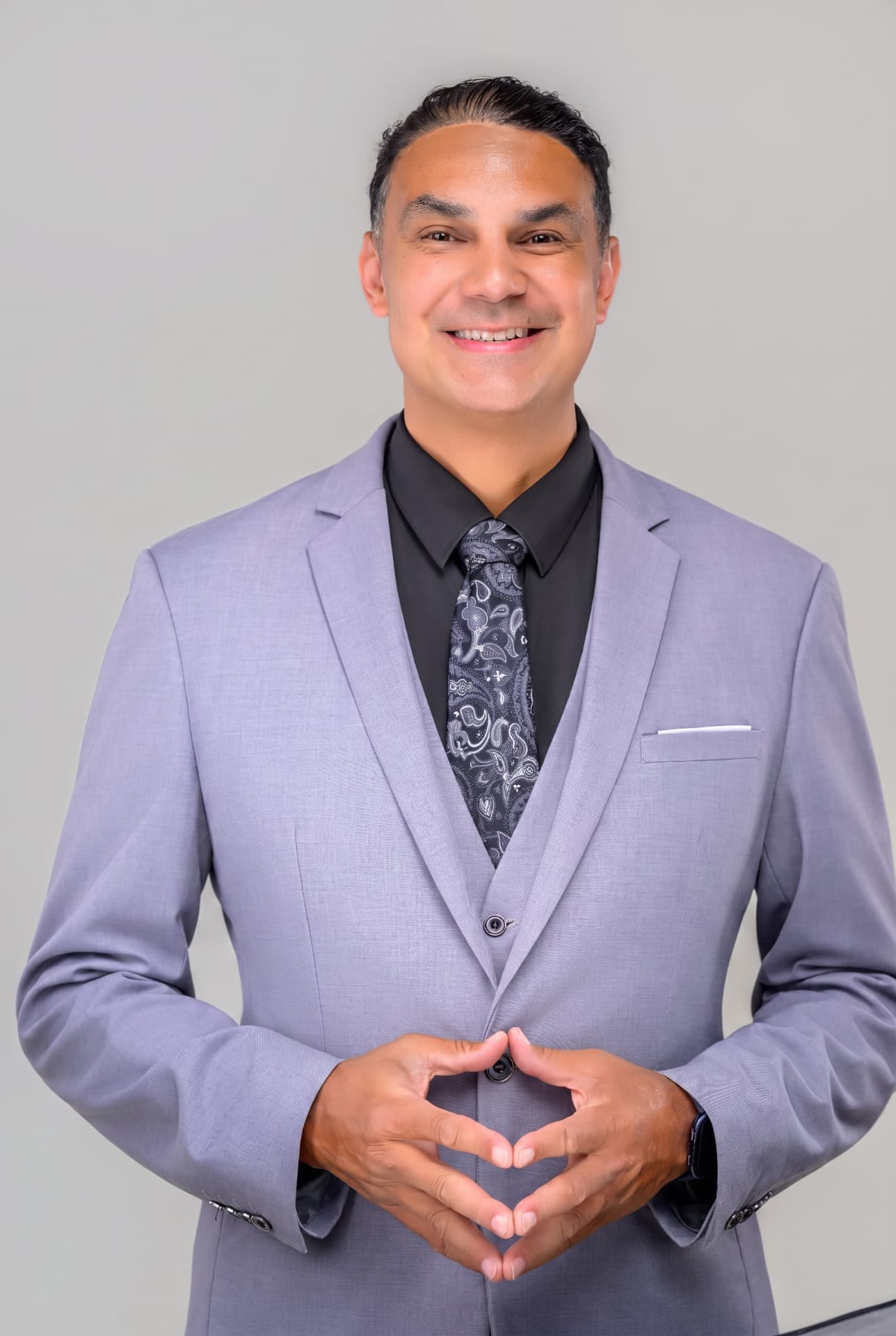 Angel Alba in a tailored lavender-grey three-piece suit and paisley tie — bilingual luxury wedding DJ and Master of Ceremonies serving Boston, Andover, and all of New England